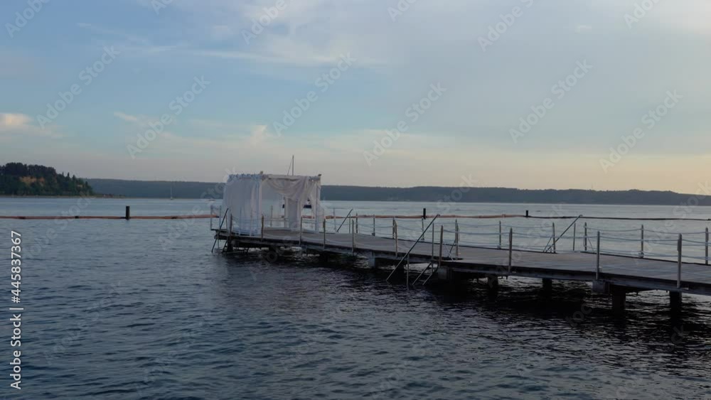 Wooden pier in the foreground and Croatian coast in the distance. Seaside town Portoroz in Slovenia. Sailboat passing by. Beautiful sunset at Adriatic Sea. Left pan, wide angle Wooden pier in the foreground and Croatian coast in the distance. Seaside town Portoroz in Slovenia. Sailboat passing by. Beautiful sunset at Adriatic Sea. Left pan, wide angle