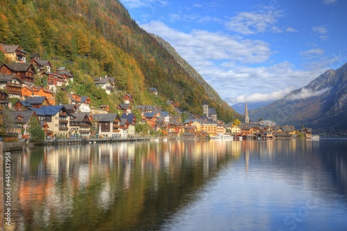 Autumn scenery of Hallstatt, an amazing lakeside village in Salzkammergut region of Austria, under blue sunny sky with beautiful reflections on smooth lake water in the brisk colorful fall season