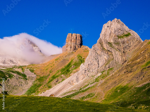 Paisaje de alta montaña de Pirineos con montañas rocosas, pastos verdes y vaca. photo