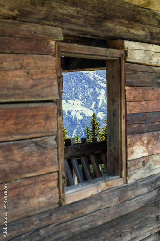 Blick durch das Fenster eines alten Bauernhauses in den österreichischen Alpen