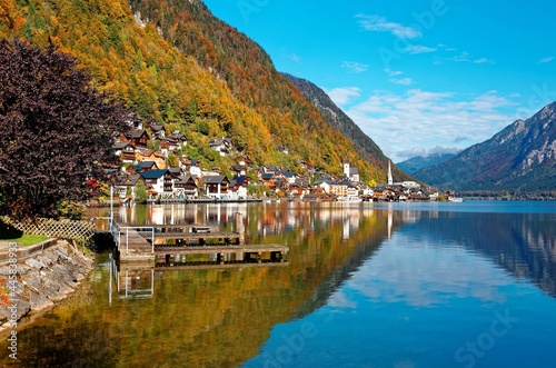 Autumn scenery of Hallstatt, an amazing lakeside village in Salzkammergut region of Austria, under blue sunny sky with beautiful reflections on smooth lake water in the brisk colorful fall season