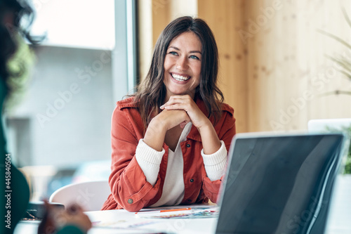 Smiling young business woman listening her partner on coworking space. photo