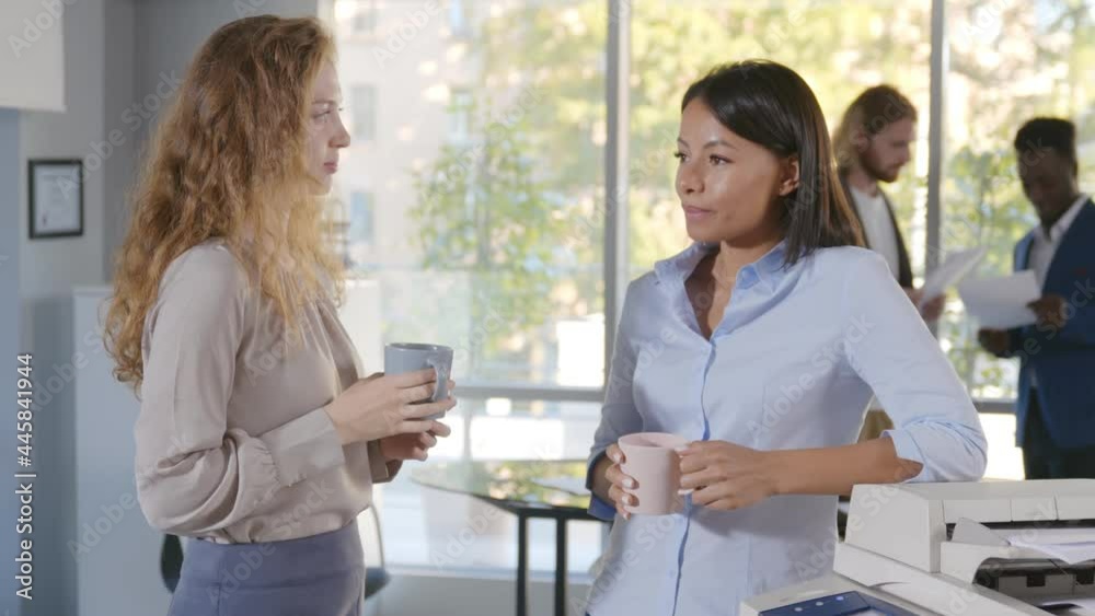 Multi-ethnic female colleagues having informal talk drink tea or coffee at break Multi-ethnic female colleagues having informal talk drink tea or coffee at break