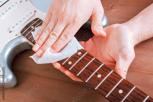 Guitar master polishing fretboard of electric guitar with cloth
