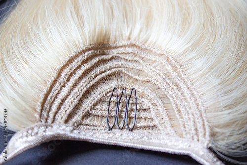 Clip in straight blonde human hair extension close-up. A tress of hair.