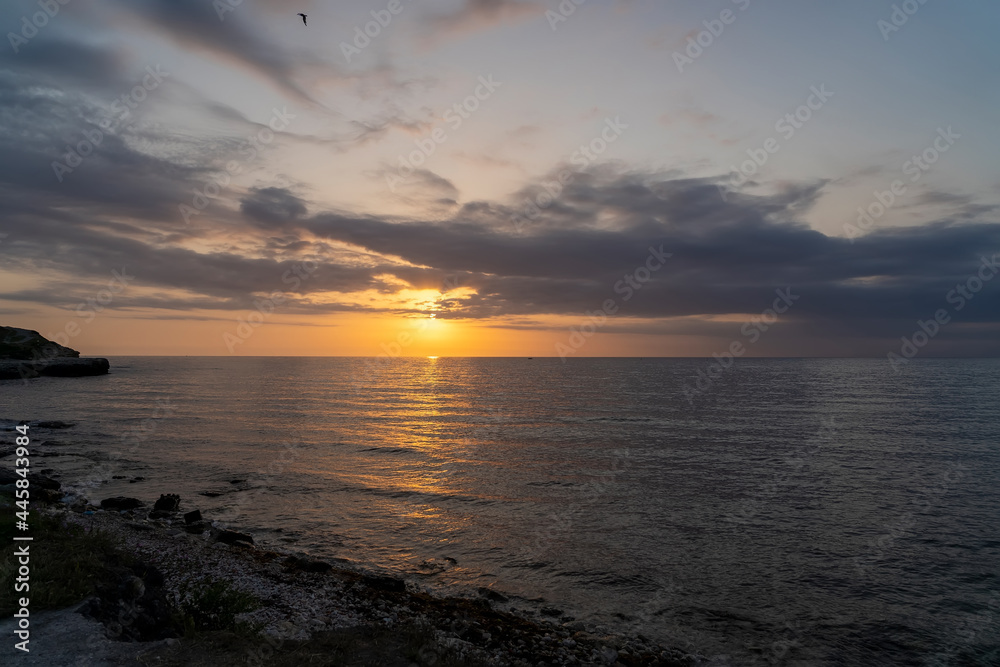 Calm sea with sunset sky and sun through clouds over. Meditation ocean and sky background. Beautiful cloudscape over sea, sunrise shot