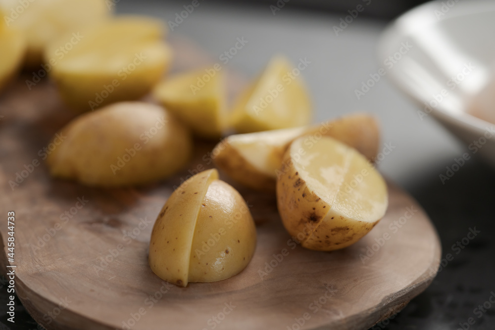 Raw washed and chopped baby potatoes ready to cook on olive wood board