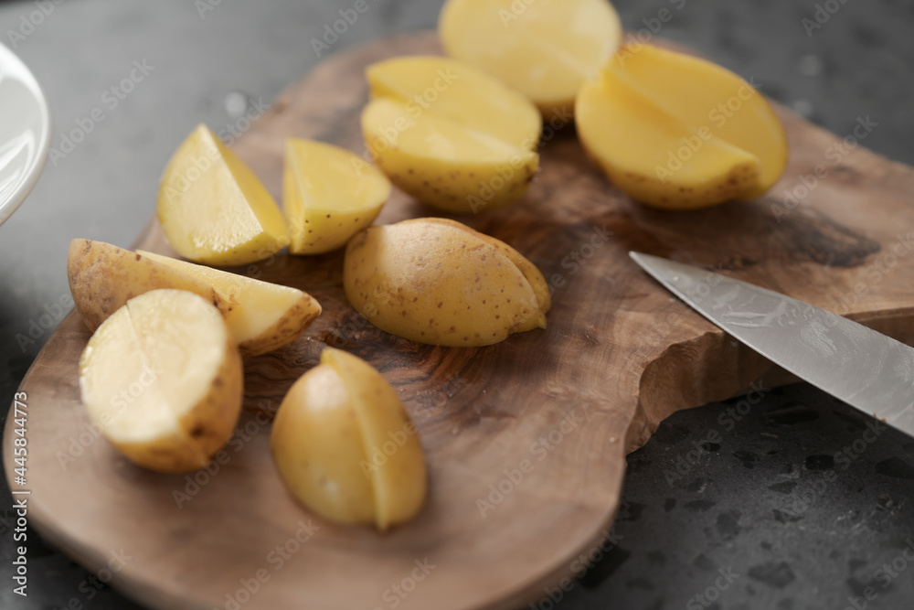 Raw washed and chopped baby potatoes ready to cook on olive wood board Raw washed and chopped baby potatoes ready to cook on olive wood board