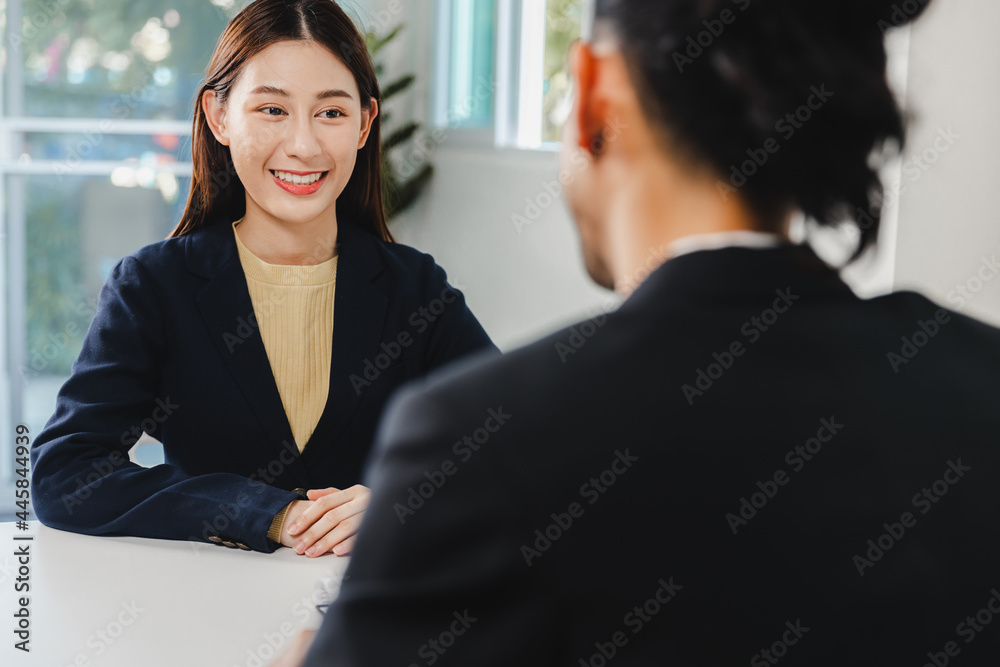 Young beautiful Asian woman candidate in black suit and long hair smiling with happiness at job interview. Young female smiling at job interview. Young beautiful Asian woman candidate in black suit and long hair smiling with happiness at job interview. Young female smiling at job interview.