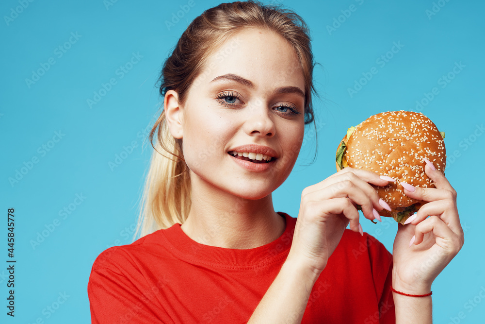 cheerful woman in red t-shirt hamburger in hands fast food blue background cheerful woman in red t-shirt hamburger in hands fast food blue background