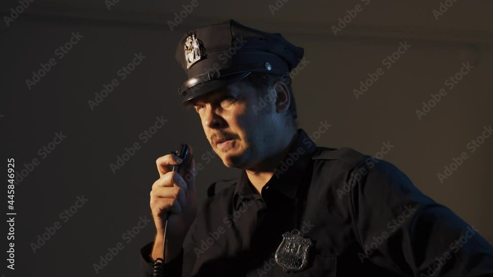 a male police officer speaks on a walkie-talkie while patrolling a close-up portrait