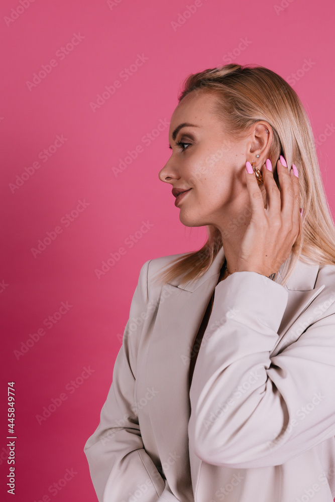 Stylish european woman in elegant beige blazer and golden jewelry, pretty makeup and big lips, posing on pink background Stylish european woman in elegant beige blazer and golden jewelry, pretty makeup and big lips, posing on pink background