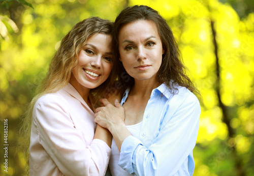 Mom and her adult daughter hold hands in a summer park, happy women © Raisa Kanareva