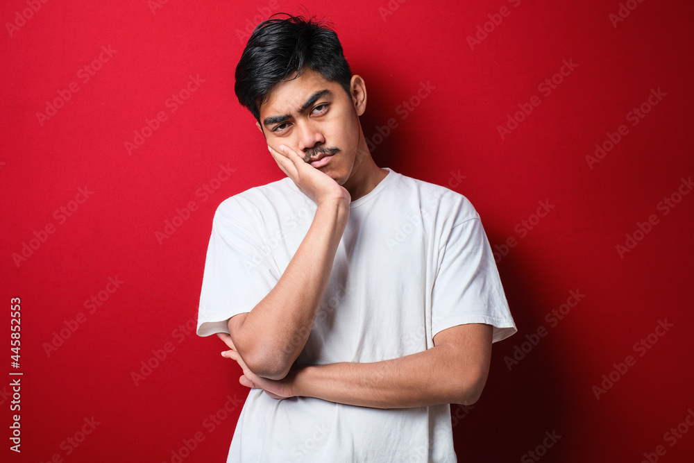 Young asian man wearing white t-shirt thinking looking tired and bored with depression problems with crossed arms. Young asian man wearing white t-shirt thinking looking tired and bored with depression problems with crossed arms.