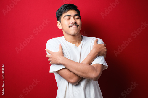 Young handsome man hugging oneself happy and positive, smiling confident. Self love and self care