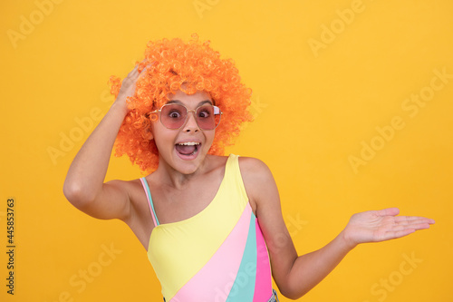 surprised child in sunglasses and swimsuit wig presenting product, copy space, surprise.