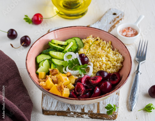 Healthy Salad Bowl with Bulgur, Cherry, Cheese, Cucumber and Walnuts on a light concrete background. Healthy food.
