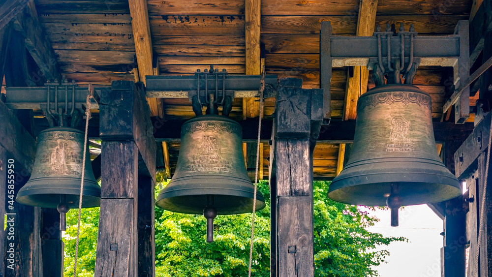 Three bells hanging in the belfry next to a Gothic church in the village of Miłoradz, Poland.