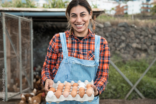 Fotografie Mature farmer picking up fresh eggs in henhouse garden - Farm people lifestyle c