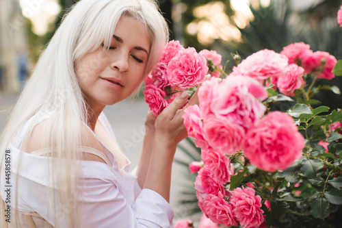 Attractive blonde woman 25 - 29 year old holding pink rose flowers in park outdoors. Healthy natural skin. Spring season. 20s. Vacation season. photo