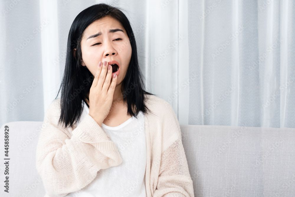 sleepless Asian woman yawning and tired from insomnia sitting on sofa sleepless Asian woman yawning and tired from insomnia sitting on sofa