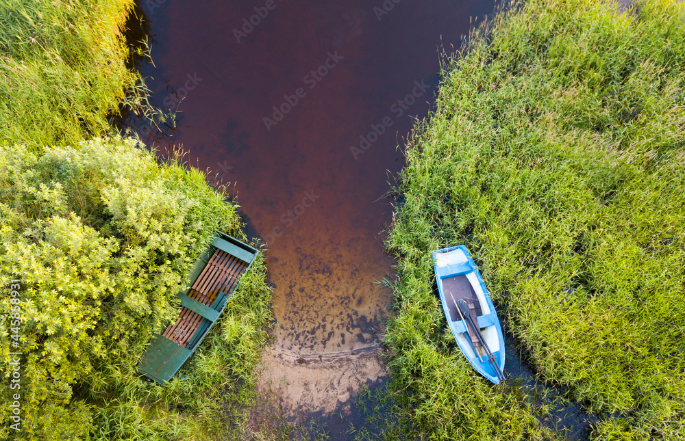 Fishing rowboat moored in the tall grass by the shore. View from above Fishing rowboat moored in the tall grass by the shore. View from above