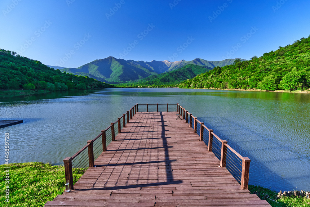 Landscape of wooden pier with beautiful lake and mountains view. Serene quiet peaceful atmosphere in nature