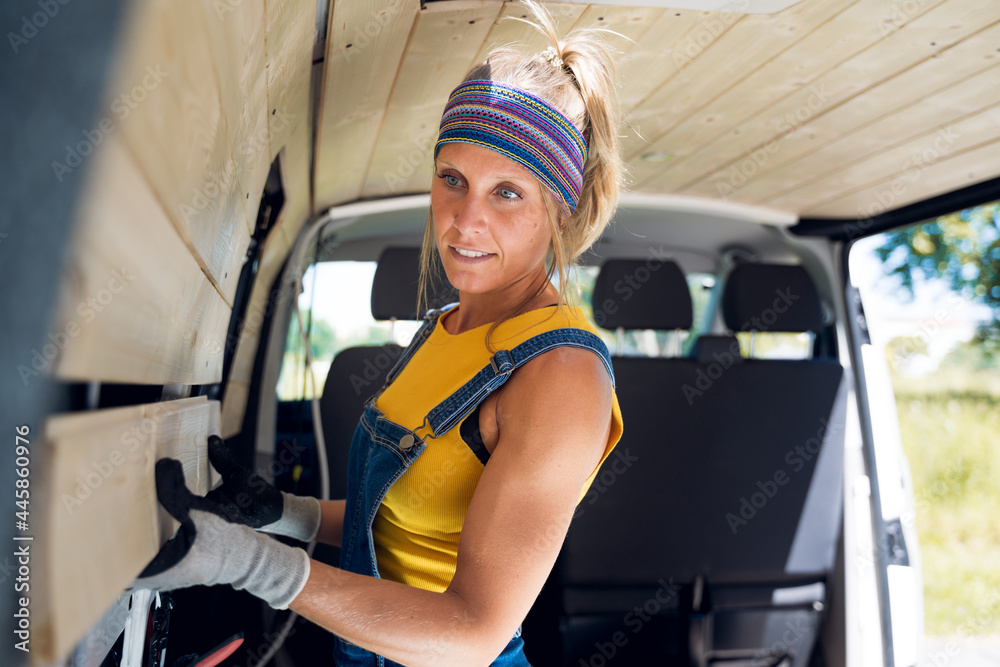 Strong woman, assembling the wooden wall of her DIY camper van. Strong woman, assembling the wooden wall of her DIY camper van.
