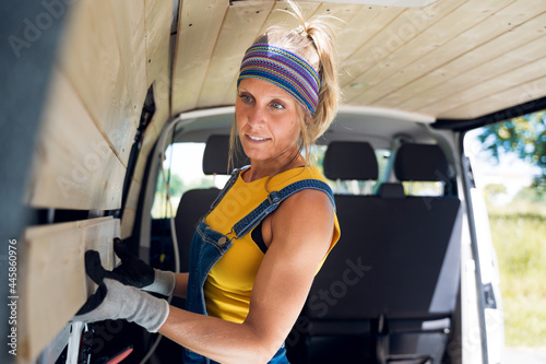 Strong woman, assembling the wooden wall of her DIY camper van.