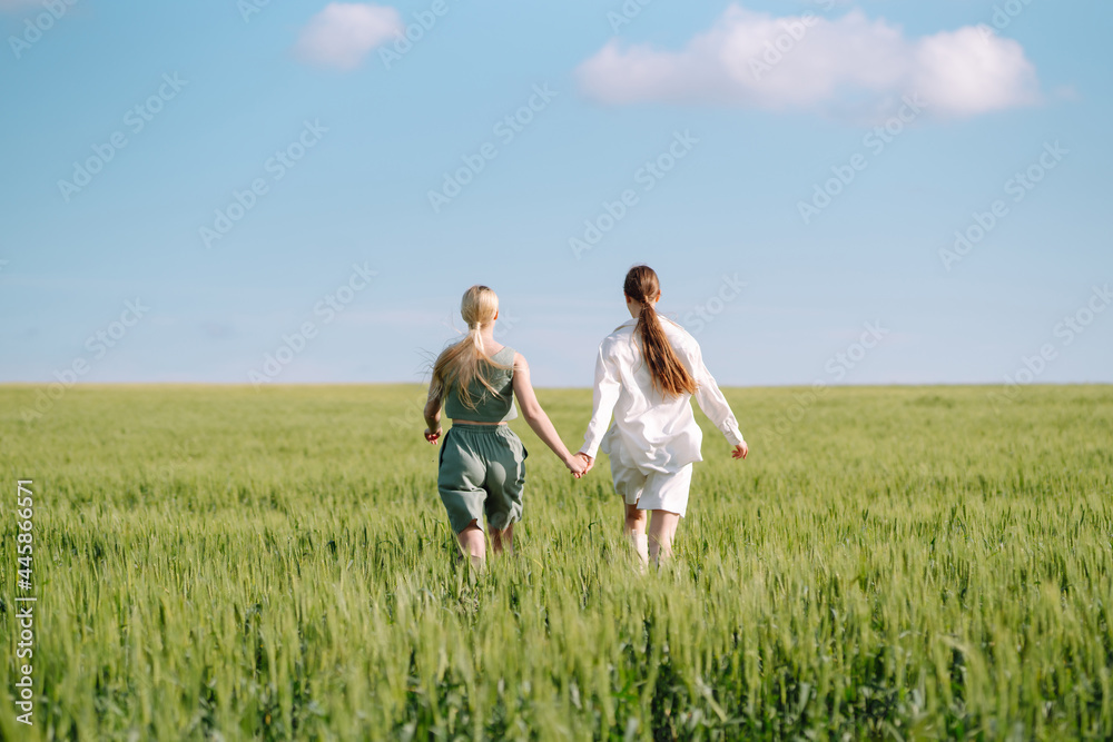 Portrait of two fair-haired girls in fashionable and stylish clothes, against the background of a field. Nature, vacation, relax and lifestyle. Fashion concept. Portrait of two fair-haired girls in fashionable and stylish clothes, against the background of a field. Nature, vacation, relax and lifestyle. Fashion concept.