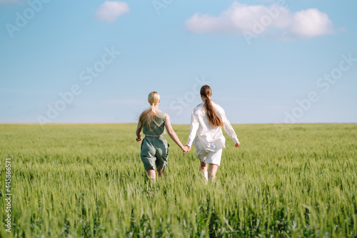 Portrait of two fair-haired girls in fashionable and stylish clothes, against the background of a field. Nature, vacation, relax and lifestyle. Fashion concept. © maxbelchenko