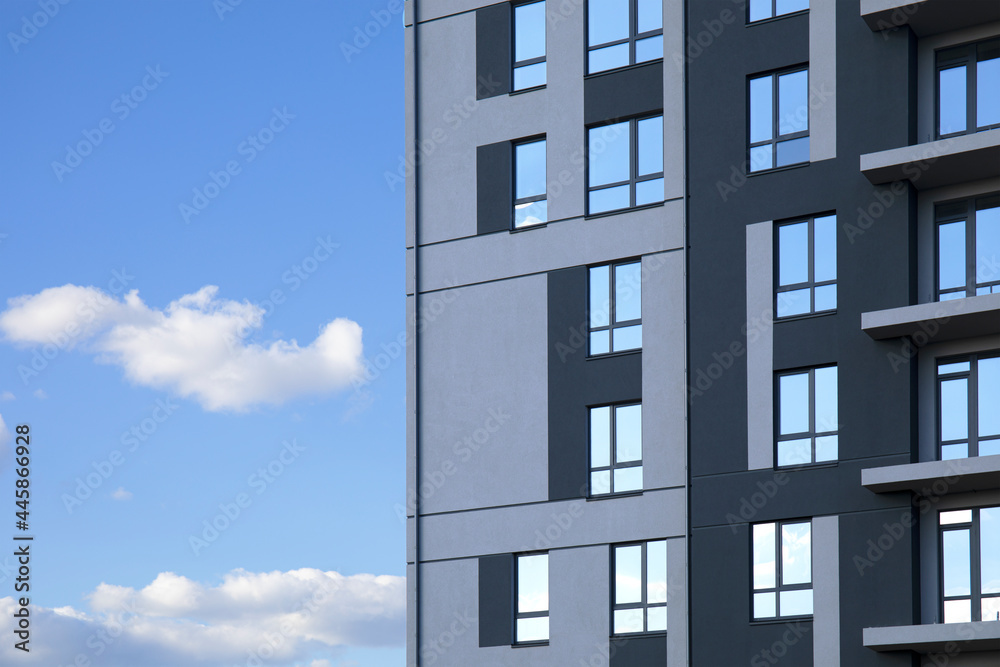 Construction of facade part of modern residential apartment building against cloudy blue sky as copy space Construction of facade part of modern residential apartment building against cloudy blue sky as copy space