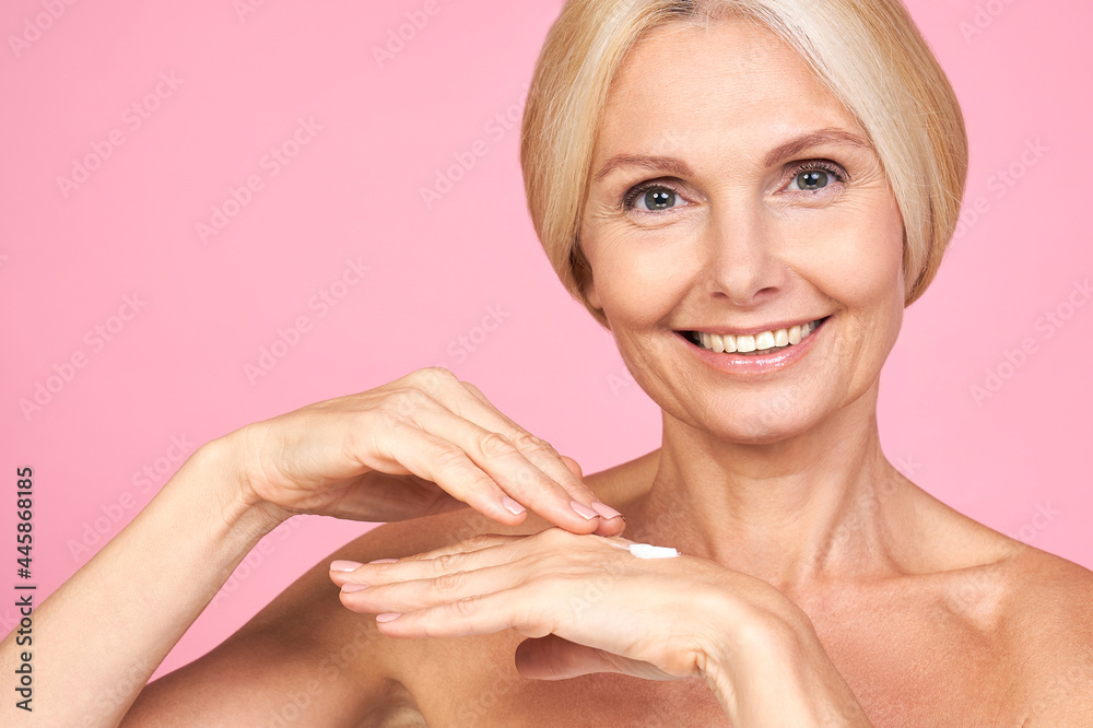 Smiling mature lady moisturizes her hands with a cream. Smiling mature lady moisturizes her hands with a cream.