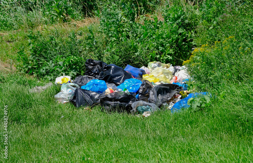 There is a pile of household waste and various household garbage thrown out by unconscious people on the green grass in nature. Stop plastic