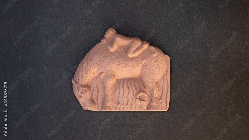 a clay figurine of a boy lying on a horse