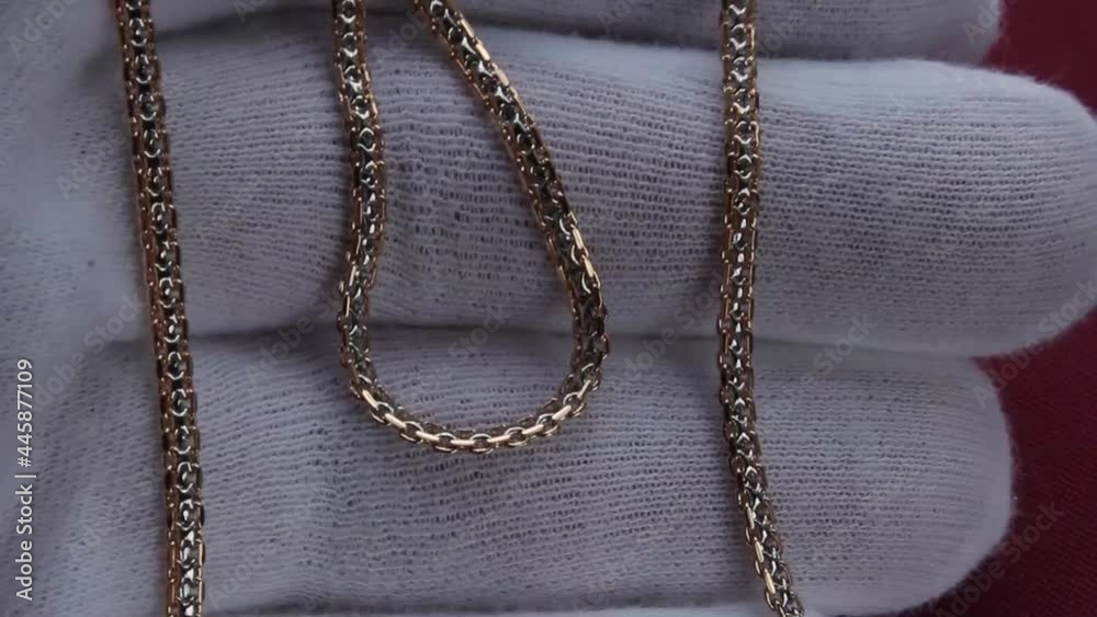 Gold chain on the hand in a white glove close-up. Jewelry is great for a gift Gold chain on the hand in a white glove close-up. Jewelry is great for a gift