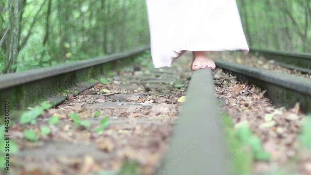 A young girl walks barefoot on the railroad. Summer weather. Around the forest. A young girl walks barefoot on the railroad. Summer weather. Around the forest.