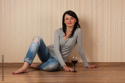 Young beautiful brunette relaxes with a glass of red wine. Relaxation, romance, leisure, lifestyle.