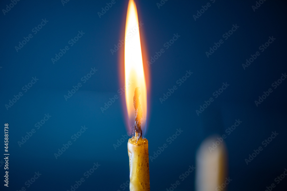 The bright flame of a dying candle on a dark background close-up. The bright flame of a dying candle on a dark background close-up.