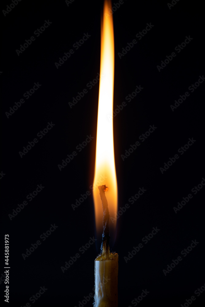 The bright flame of a dying candle on a dark background close-up. The bright flame of a dying candle on a dark background close-up.