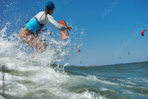 Kite surfer woman jumps with kiteboard in transition and throws up the board