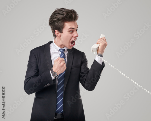 Irritated salesman shouting into telephone receiver photo