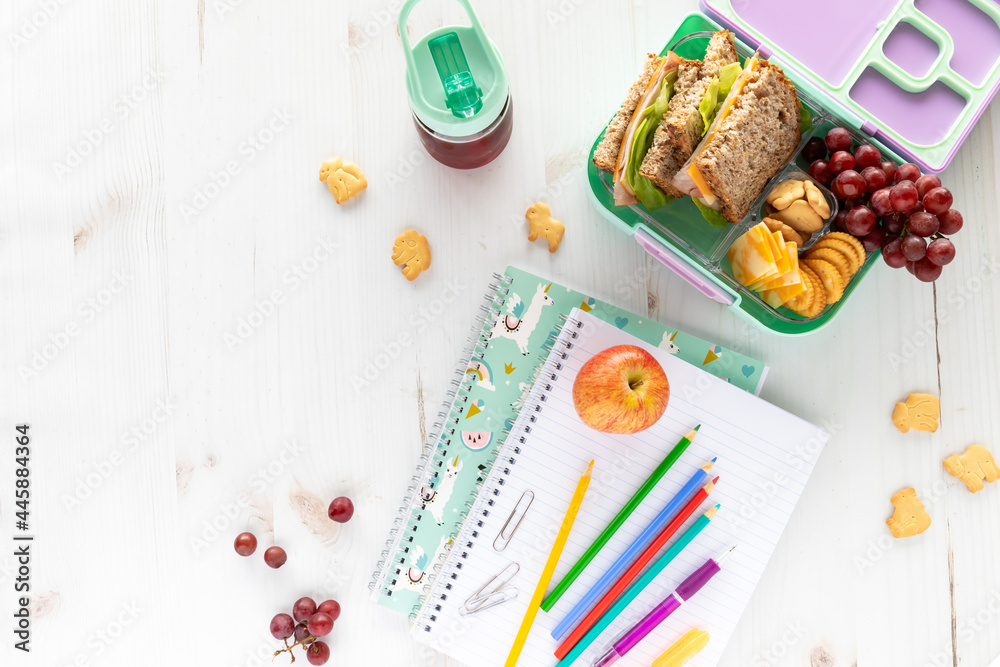 Top down view of school supplies and lunch on a light background