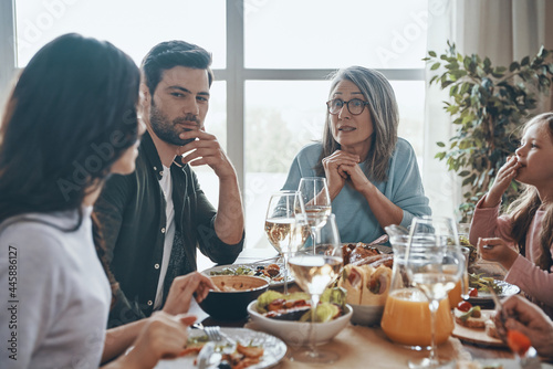 Happy multi-generation family communicating and smiling while having dinner together