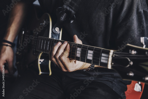 a guy in a dark T-shirt plays an electric guitar on a dark background