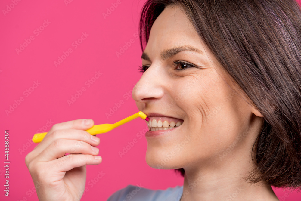 Beautiful happy young woman with single tufted toothbrush on blank pink background Beautiful happy young woman with single tufted toothbrush on blank pink background