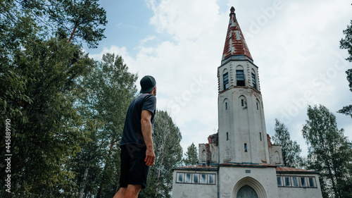 Man stend and looking on abandoned Finnish Lutheran church in the village Lumivaara photo