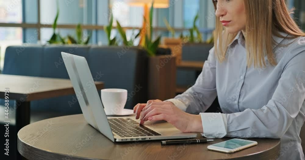 Closeup shot young woman using laptop in restaurant. No face Closeup shot young woman using laptop in restaurant. No face