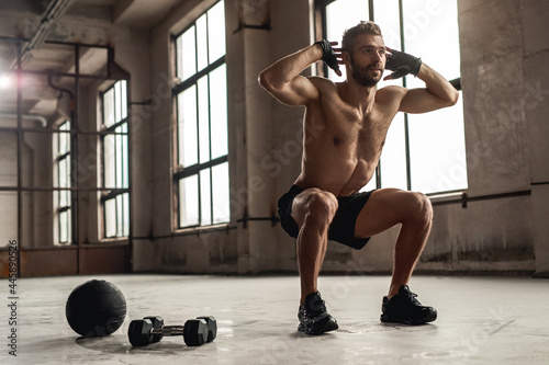 Muscular man doing squats in gym photo