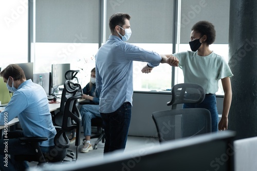 Businessman and businesswoman with medical mask in office. Greetings in Covid-19 time